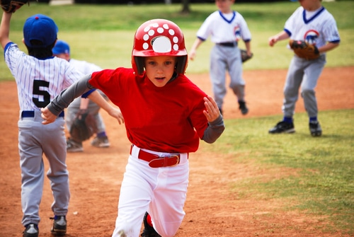 A young boy running in a baseball game while wearing a helmet.