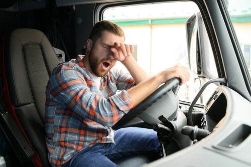 A man yawning in his truck, unable to get through his day thanks to untreated bruxism.