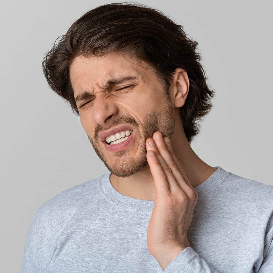 A man suffering from jaw pain caused by untreated TMJ.