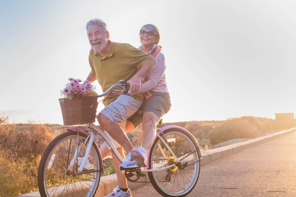 Elderly couple with dentures rides a bicycle together in Grove City.