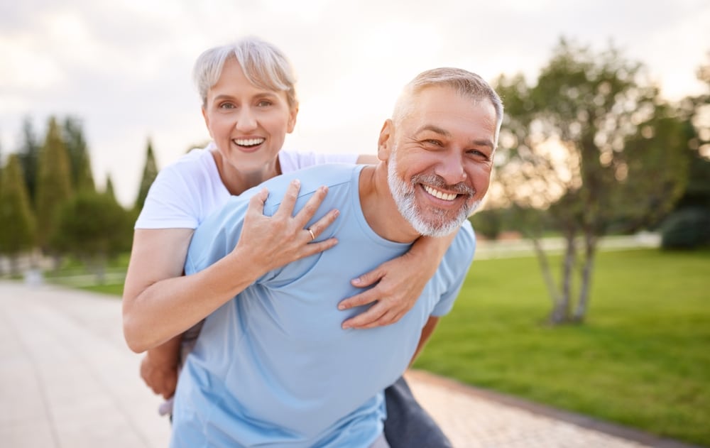 An older man and woman smiling confidently with restored teeth.