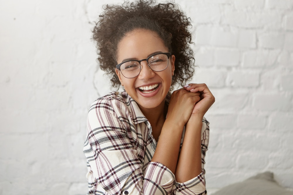 Smiling woman with curly hair and glasses shows off her new smile after cosmetic dentistry in Grove City