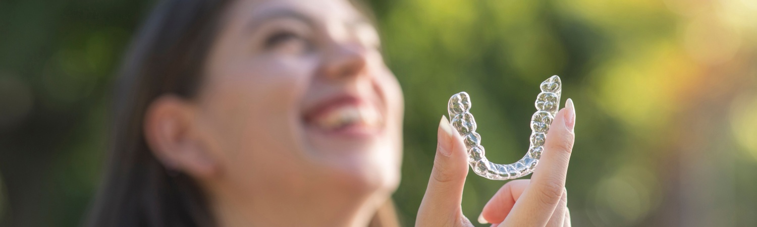 A woman holding Invisalign clear aligners in Grove City.