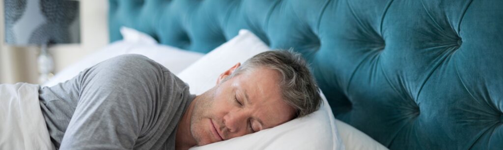 A man laying in bed, sleeping peacefully.