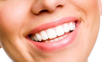 Close-up of a smiling mouth showing white teeth and pink lips.