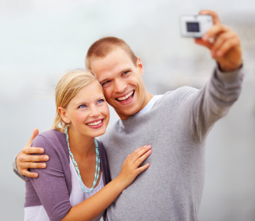 A young couple smiling and taking a photo together after teeth whitening in Grove City.